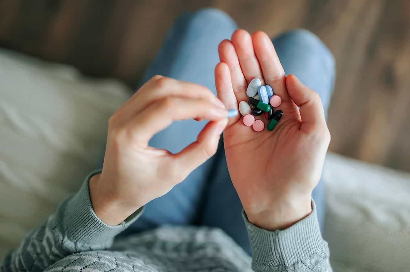 Mujer sosteniendo diferentes pastillas y antibióticos