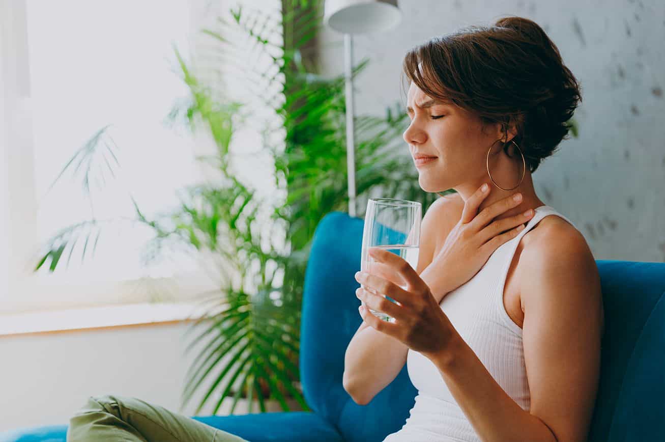 Mujer con dolor de garganta tomando agua